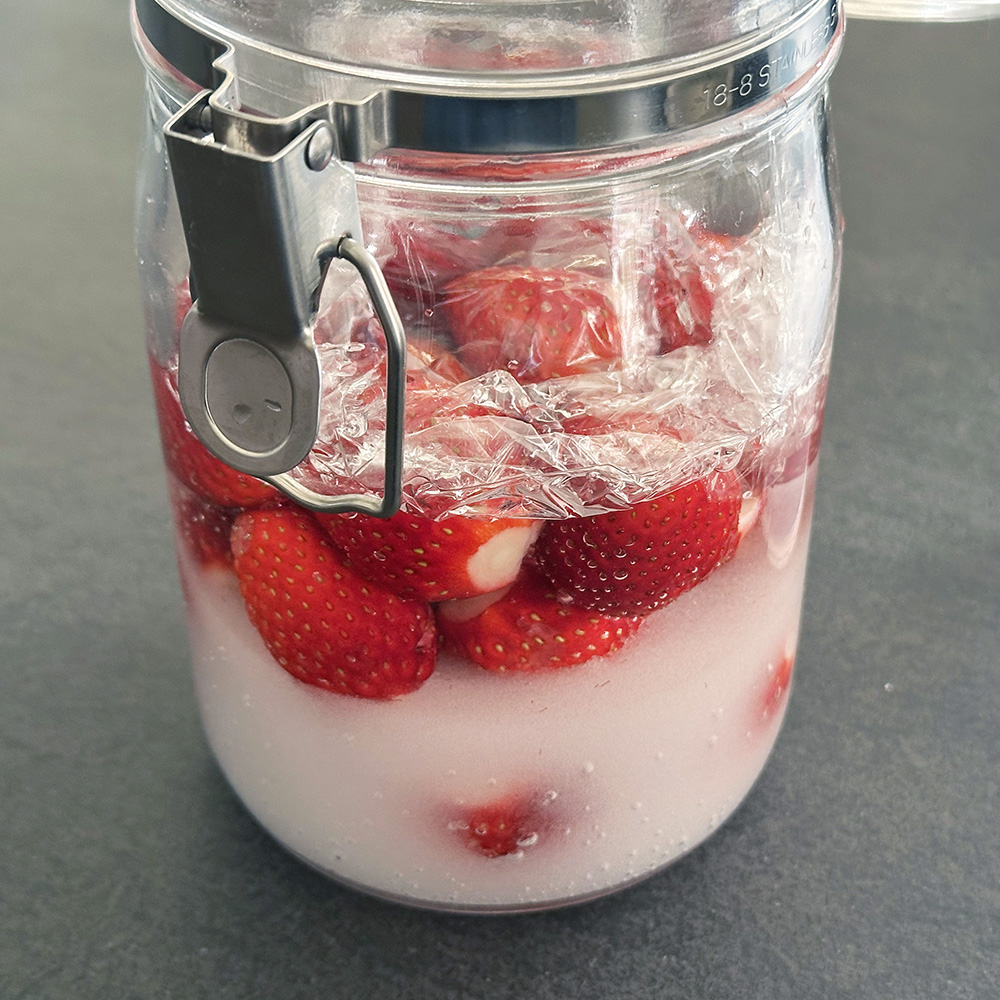 密封瓶に苺、グラニュー糖、水を入れて漬け込みスタート。1日に1回、清潔なヘラで苺を傷つけないように優しく撹拌します。6日間漬け込みます。